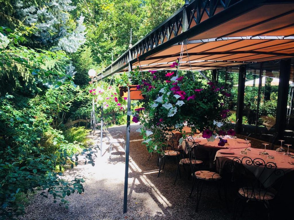Terrazza con tavoli apparecchiati e fiori appesi.