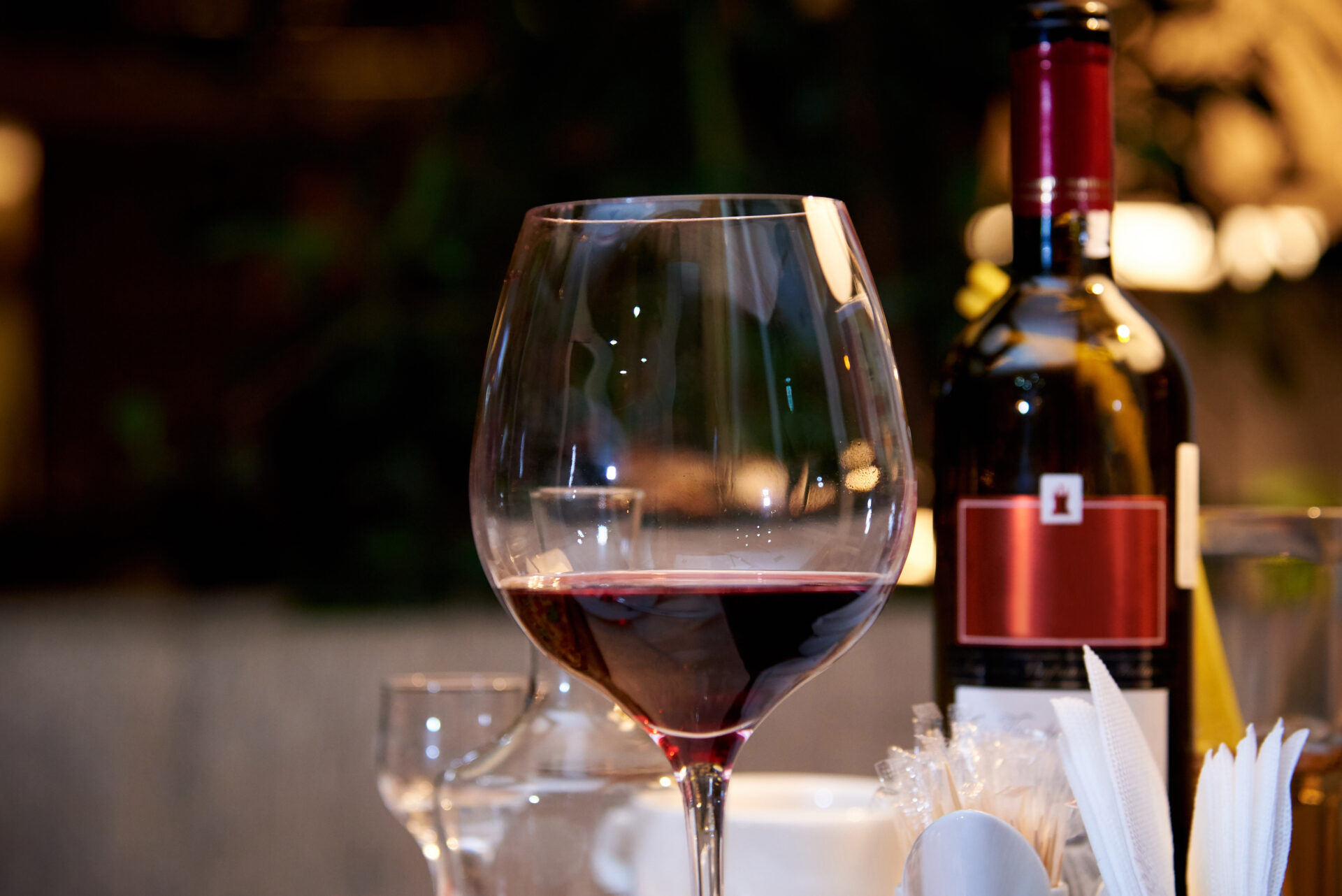 Bicchiere di vino rosso e bottiglia su tavolo.