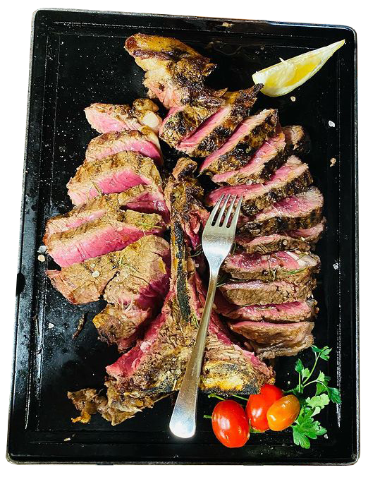 Bistecca tagliata su piatto con pomodori e limone.