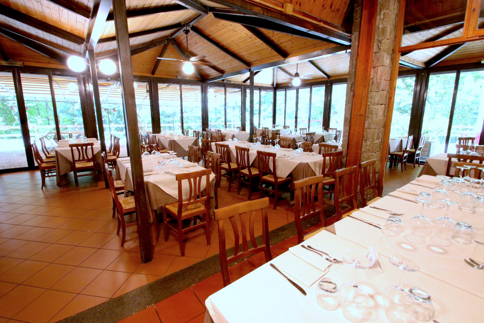 Ristorante con tavoli apparecchiati e ampie vetrate.
