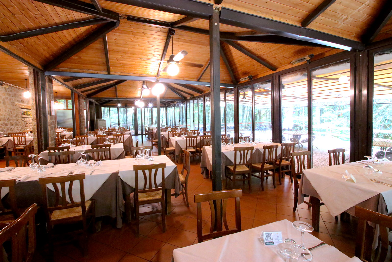 Ristorante con tavoli apparecchiati, soffitto in legno.