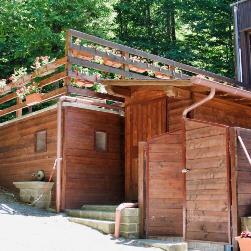 Capanno in legno con fioriere e vegetazione circostante.