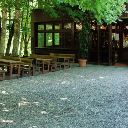 Area esterna con tavoli e sedie in legno.
