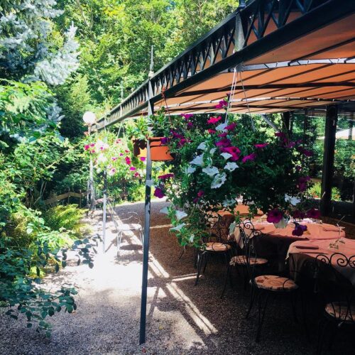 Terrazza con tavoli apparecchiati e fiori appesi.