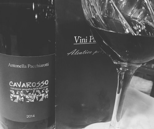 Bottiglia di vino rosso e bicchiere su tavolo.