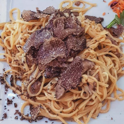 Tagliatelle con tartufo su piatto bianco.