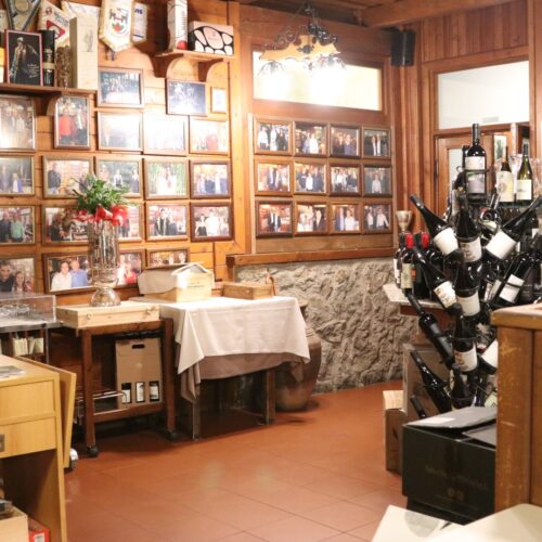 Interno di un ristorante con foto e bottiglie di vino.