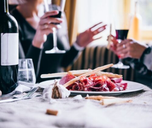 Bottiglia di vino e piatto di salumi su tavola.