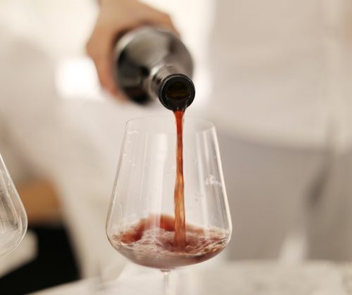 Vino rosso versato in un bicchiere trasparente.