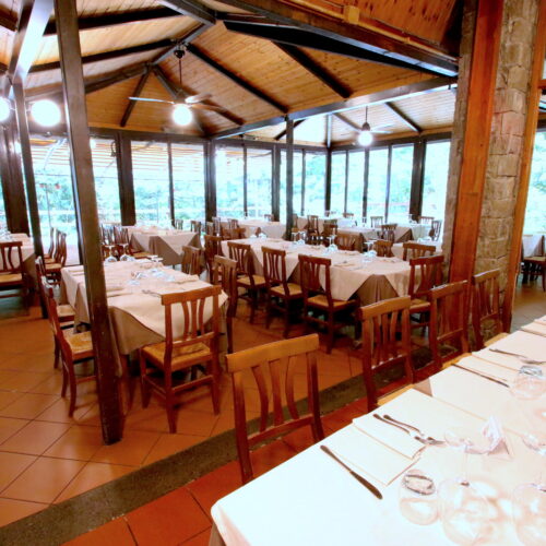 Ristorante con tavoli apparecchiati e ampie vetrate.