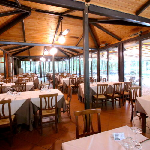 Ristorante con tavoli apparecchiati, soffitto in legno.