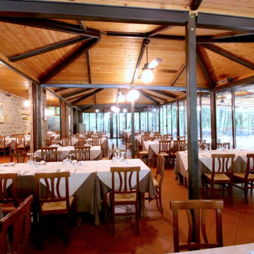 Ristorante con tavoli apparecchiati, interni in legno.