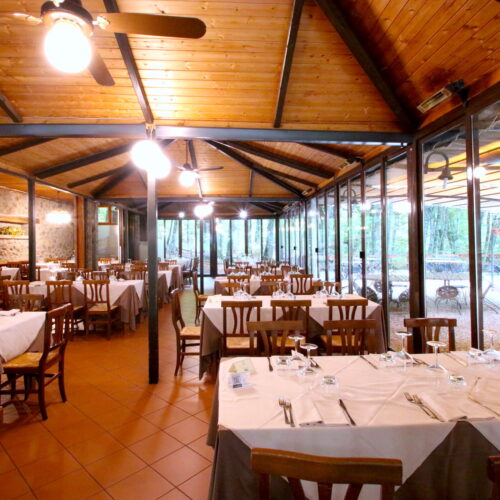 Ristorante con tavoli apparecchiati e soffitto in legno.